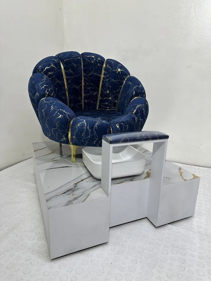 Combo Pedicure con silla azul de patas doradas y lavapiés sobre tarima tipo mármol, en el showroom