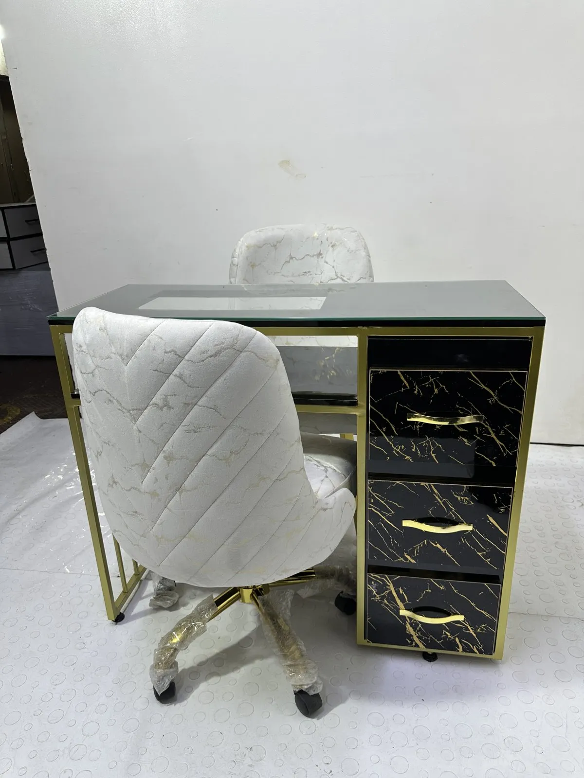 Esmaltero dorado con tope de vidrio, cajones en mármol negro y sillas en piel de durazno, foto real