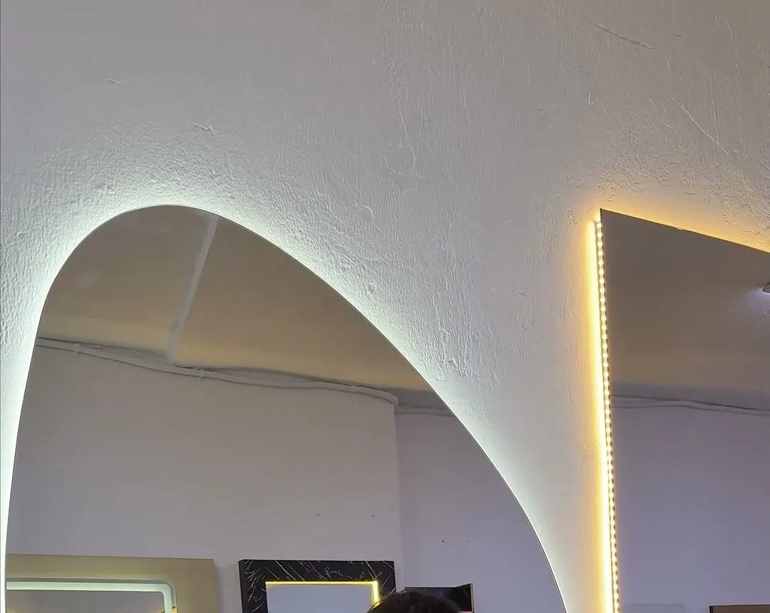Borde de un espejo asimétrico con luz LED en el showroom de Muebles Pulido